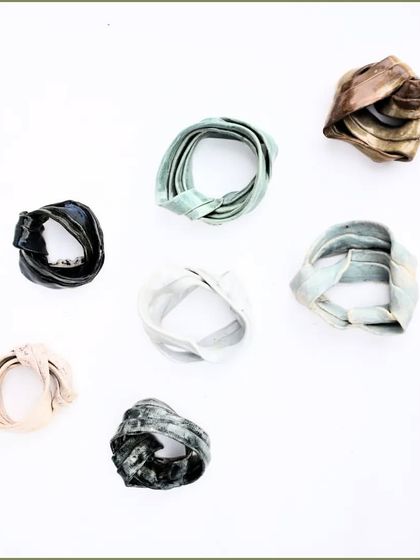 'Swirls of Life'. These small, ribbon-like ceramic sculptures can also be worn as unique, artistic brooches or pendants.