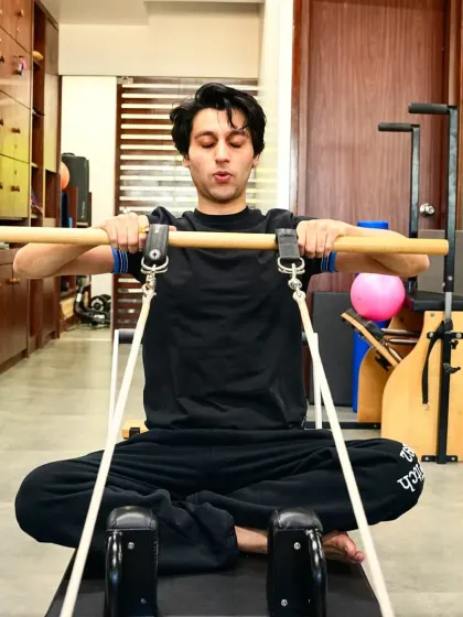 A seated arm exercise on the reformer helps to strengthen the back and shoulders while promoting good posture. This client demonstrates the focus and control that is central to the Pilates method.