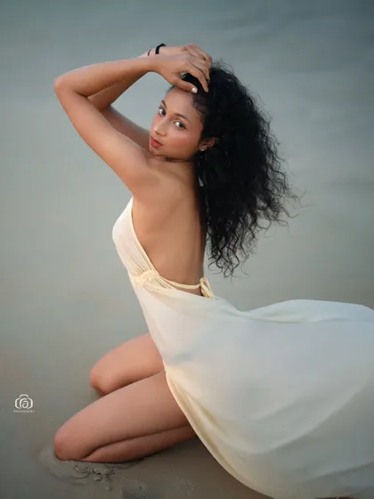 A kneeling pose on the sand, with the model looking back at the camera. The soft light and the gentle movement of the dress create a beautiful and intimate portrait.