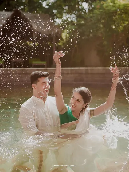 A fun and playful moment as the couple splashes in the water of a temple pond, their laughter infectious.