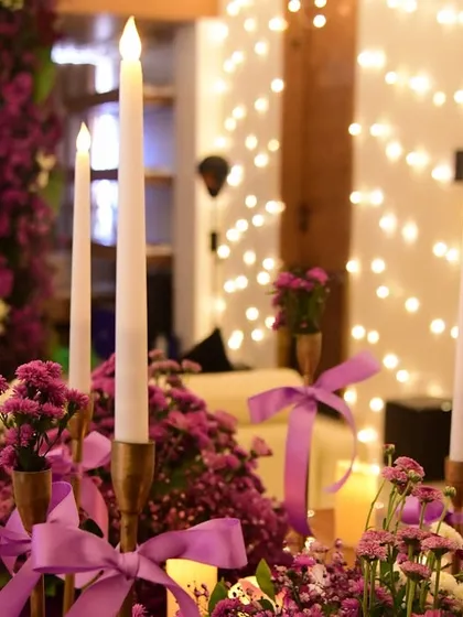 A close-up of the candle and floral details from the purple-themed party. The satin ribbons on the candle holders tie the whole color scheme together.