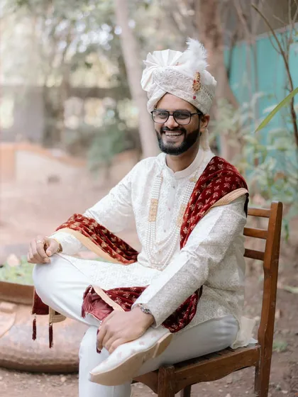 A relaxed and joyful portrait of the groom, seated outdoors. His genuine smile shows the happiness of the wedding day.