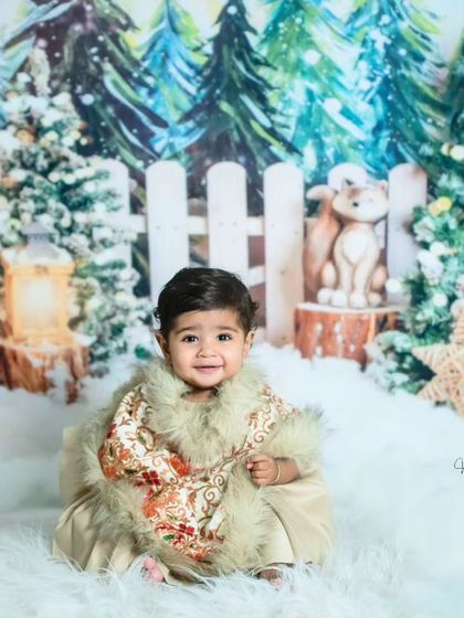 A wider view of the 'Winter Wonderland' set, complete with a white picket fence, lanterns, and reindeer props. This baby looks right at home in this magical Christmas scene.
