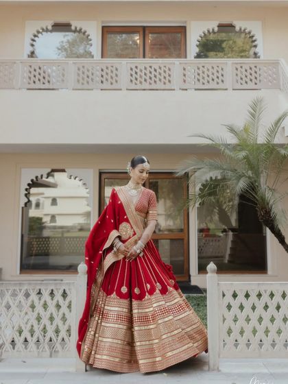 A full-length shot capturing the grandeur of the bride's outfit and the stunning architecture of the venue.