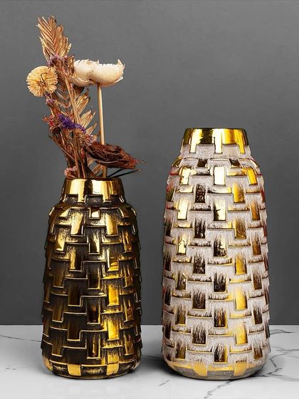 This pair of decorative vases features a textured, woven-like pattern in black and white with a gold finish. They are perfect for holding dried flowers or standing alone as modern sculptural pieces.