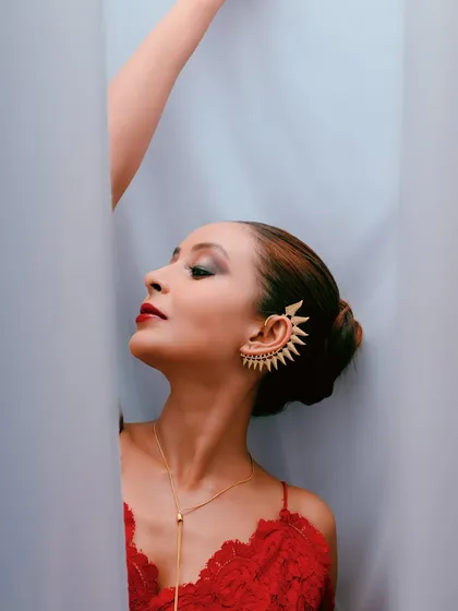 A close-up shot with eyes closed, conveying a sense of serenity and focusing on the textures of the dress and jewelry.