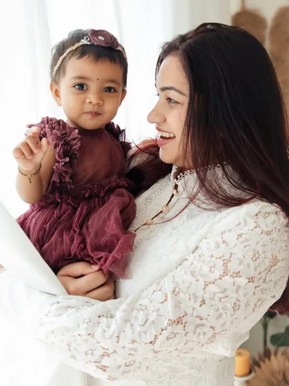 A mother and her daughter share a sweet moment by the window. The soft light and their gentle interaction create a serene and loving portrait.