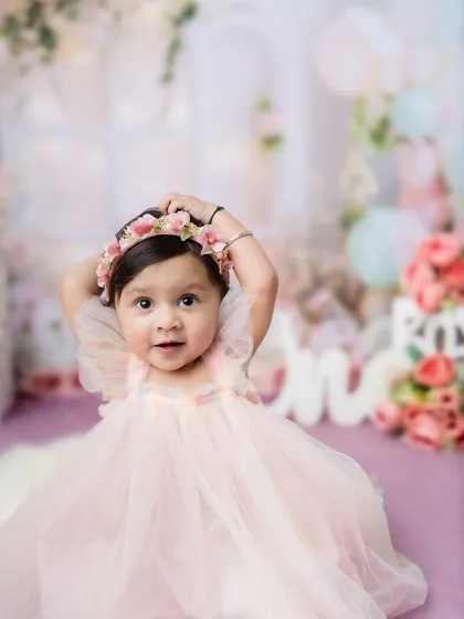 A beautiful one-year-old princess in a pink dress, surrounded by a dreamy floral setup.