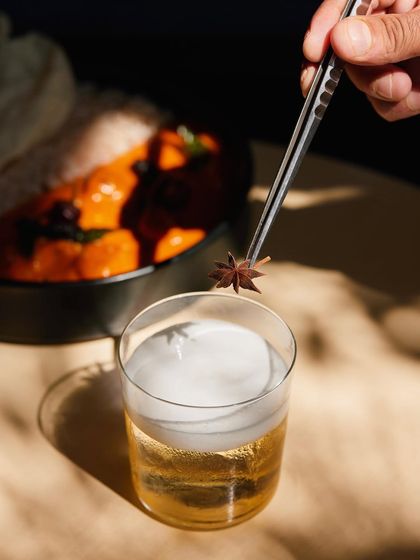 The final garnish of star anise is placed on the airy foam of our Cuban Sour, adding a hint of spice and visual elegance.