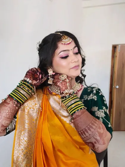 The client adjusting her jewelry, giving a candid look at her complete traditional attire.
