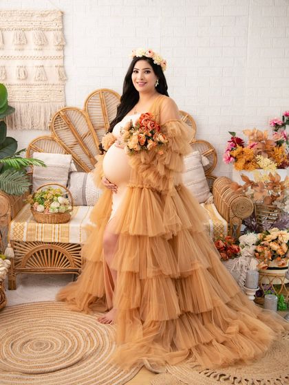 A full-length portrait of the mother-to-be in a magnificent tiered tulle gown. Holding a bouquet, she looks like a goddess in a sun-drenched, earthy setting.