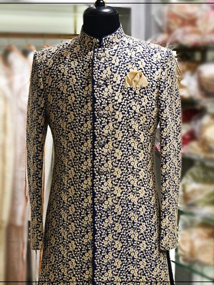 A navy blue Indo-Western sherwani with dense, gold floral embroidery. This is a rich and opulent look, perfect for a groom or his close family.