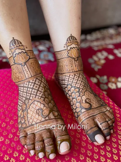 An intricate bridal foot mehendi with peacock motifs and architectural domes. The design is dense and detailed, perfect for a bride.