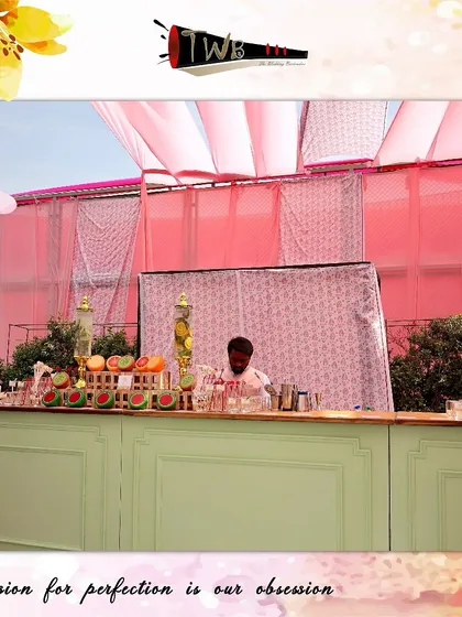 A vibrant and colorful Mehendi bar setup at Taj Bhopal, featuring a pastel green bar front, pink drapes, and an array of fresh fruits that add to the festive and joyful atmosphere.