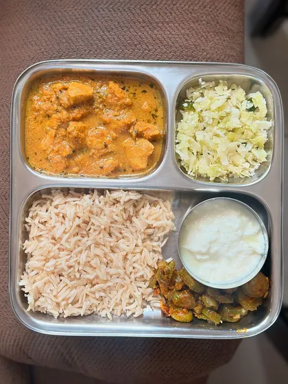 A non-vegetarian meal of brown rice, chicken curry, sautéed cabbage, and ivy gourd with curd. This is a well-balanced and high-protein lunch.