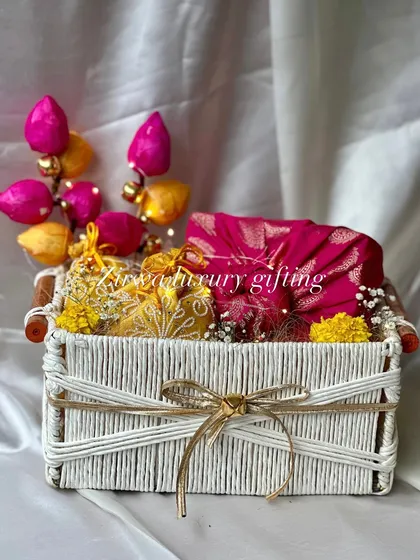 This colourful Lohri hamper in a white woven basket is so vibrant. The pink and yellow potlis, along with a brocade fabric piece, make it a joyful and traditional gift.