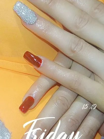 A chic and simple design featuring a rich, burnt-orange polish on square nails, paired with a single, statement-making silver glitter accent nail.