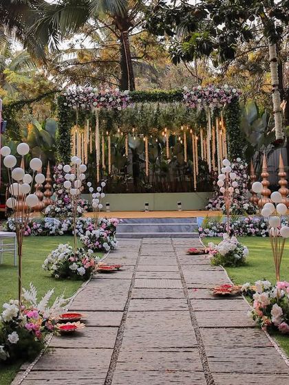 A wide shot of an elaborate wedding setup on our main lawn. The hanging floral arrangements and decorated aisle create a grand and luxurious feel.