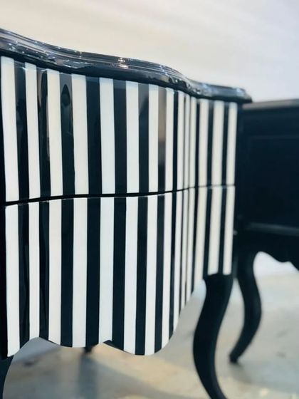 A close-up of a bold, black-and-white striped chest of drawers in progress. The high-gloss finish and classic curved legs showcase our ability to execute intricate and daring designs.
