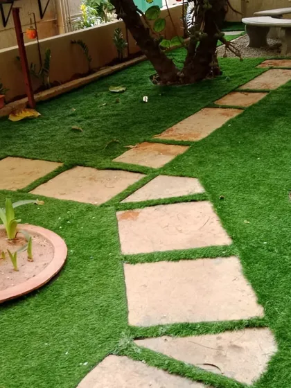 In this garden, I integrated artificial grass around existing trees and an irregular flagstone path. This approach maintains the natural, rustic feel of the space while eliminating the hassle of mowing around obstacles.