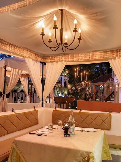 A look inside one of our larger cabanas, perfect for small groups or a spacious dinner for two. The chandelier adds a touch of classic elegance to the alfresco experience.