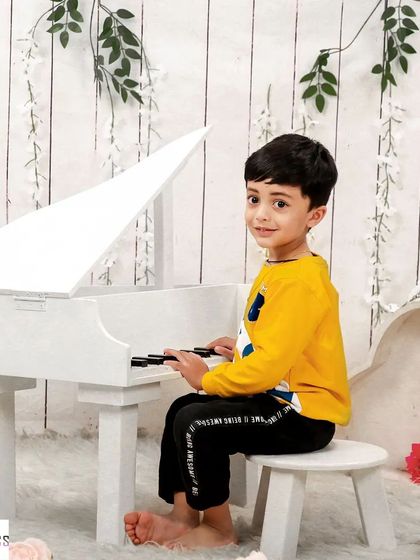 A little musician at his grand piano. This simple and elegant studio setup is perfect for capturing a child's love for music.