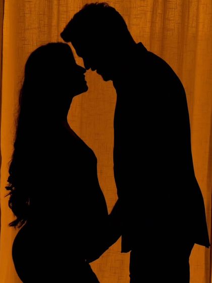 A classic silhouette of a couple against a warm, neutral backdrop. This technique creates a timeless and intimate portrait that focuses on the shape and connection between the parents-to-be.
