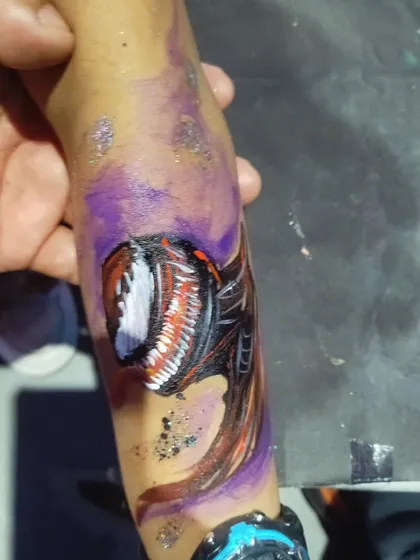 An arm painting of Venom, showing the character's head and part of its body. The purple background and glitter add an otherworldly feel.