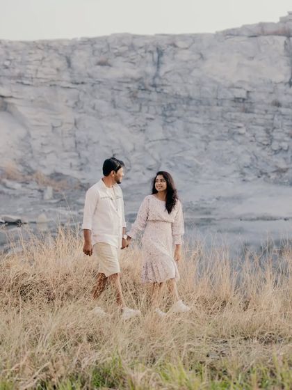 A similar shot of the couple walking hand-in-hand through the field, capturing their natural interaction and movement.
