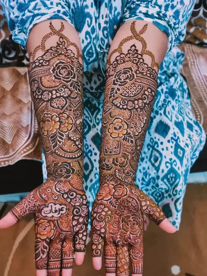 The beautiful and intricate mehndi for bride Kulsum, featuring her groom's name 'Irfan' on her palm.