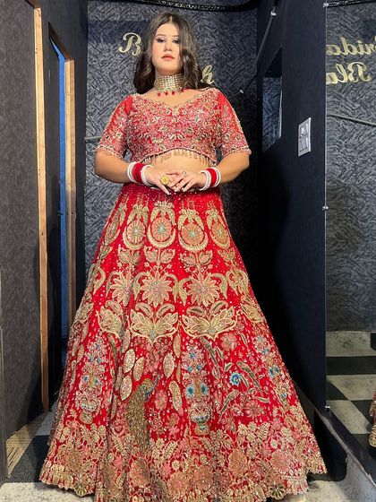 A classic pose in a traditional red bridal lehenga. The detailed craftsmanship and rich color make it a perfect choice for the main wedding ceremony.