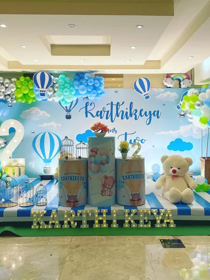 A whimsical hot air balloon theme for a second birthday. I used a sky-blue backdrop, cloud-like balloons, and themed pedestals to create a feeling of floating in the air.