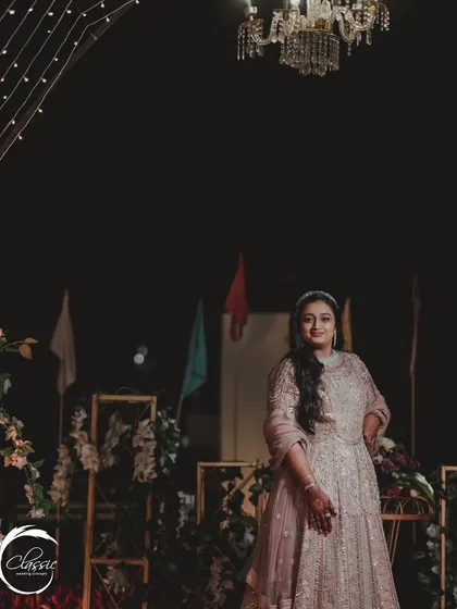 The bride, looking radiant against the backdrop of her Sangeet decor. The soft lighting and elegant floral arrangements are designed to make everyone look and feel their best.