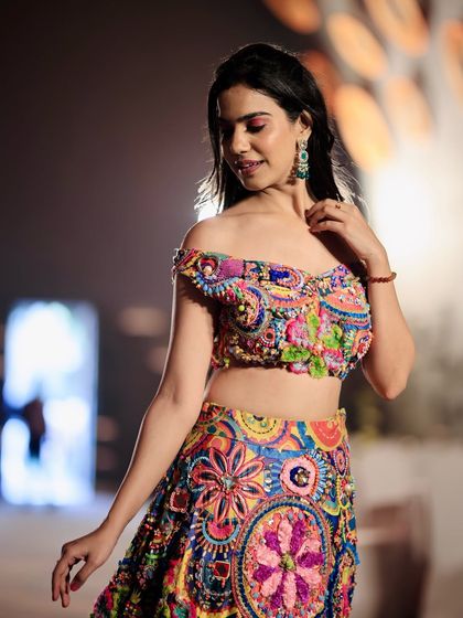 A close-up look at the intricate threadwork and off-shoulder design of this vibrant lehenga. I ensure that the fine details of the garment are clearly visible.