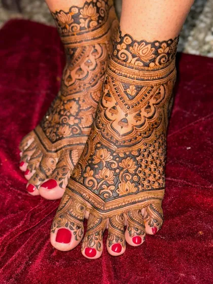 Another angle of the intricate lotus feet design, set against a rich red velvet background. The dark henna paste stands out beautifully, promising a gorgeous stain.