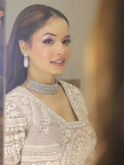 A beautiful bride looking in the mirror, ready for her reception. The makeup is soft and shimmery, perfect for an evening of celebration.