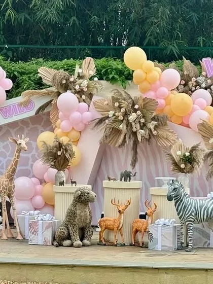 A wide view of the "Two Wild" setup, showcasing a variety of friendly animal props like an elephant, zebra, and deer. The pastel balloon garland and pink safari jeep complete this adorable party scene.