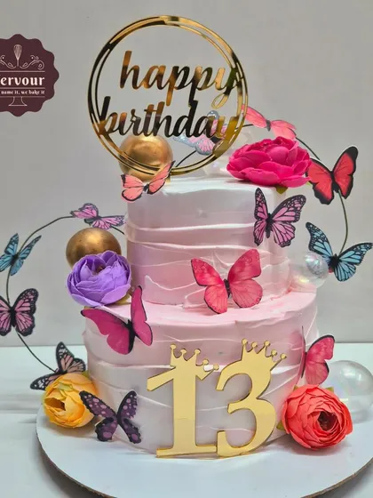 A beautiful butterfly-themed cake for a 13th birthday. This two-tier chocolate truffle cake is adorned with colourful butterflies and fresh flowers.