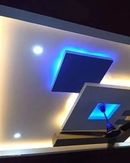 A sleek and modern design featuring a floating panel with blue backlighting. The combination of warm cove lighting and cool accent light creates a sophisticated, layered effect.