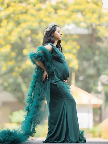 A powerful and elegant side-profile portrait, highlighting the baby bump and the flowing green gown.