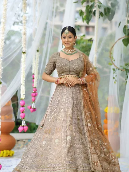 A full-length shot of the bride in her gorgeous pastel lehenga. The makeup is soft and glowing, with a red flower in her hair adding a beautiful pop of color.