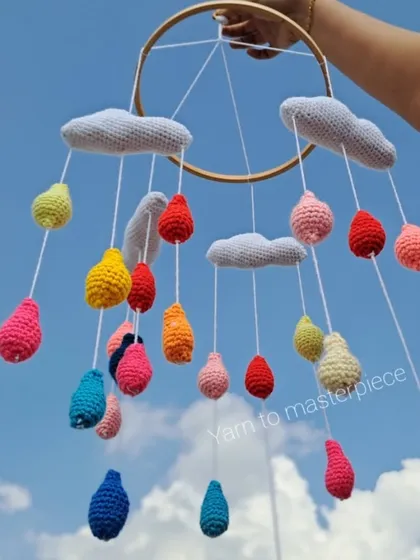 The cloud and raindrop mobile held up against the sky, showing how beautifully the colors pop. Each element is soft and lightweight.