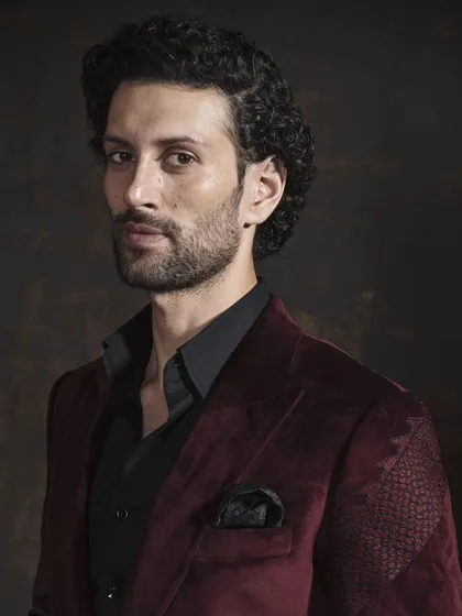 A closer portrait shot of the maroon velvet blazer, highlighting the peak lapels and how the fabric drapes. Elegance is in these details.