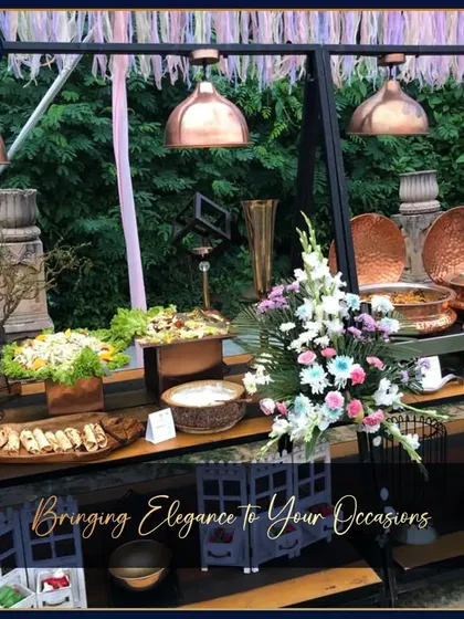 Another angle of our rustic-chic outdoor buffet. The setup features industrial-style frames, copper lamps, and lush greenery, showing how we tailor our design to your event's theme.