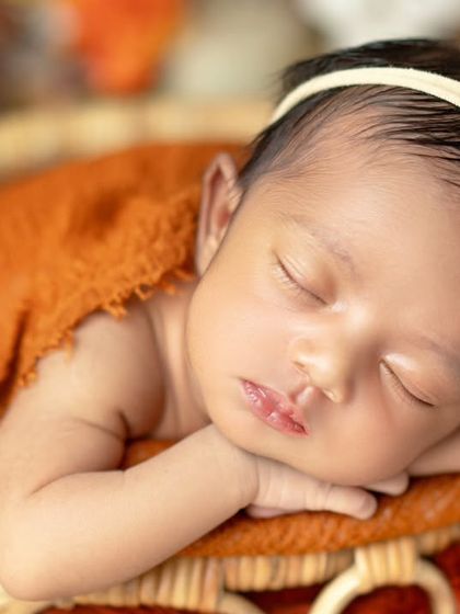 A close-up of a sleeping beauty. The warm, rustic tones and floral headband add a touch of sunshine to this newborn portrait.