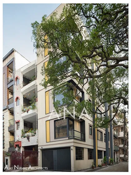 The Yellow Line Apartment building situated within its neighborhood context. The design stands out for its modern aesthetic while respecting the scale of the adjacent properties, using a tree to frame its verticality.