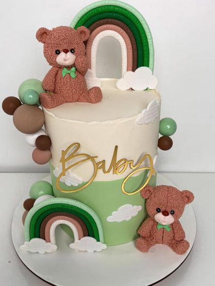 A modern and chic baby shower cake in a sage green and brown color palette. This design features two adorable, textured teddy bears, boho-style rainbows, and a golden "Baby" script.