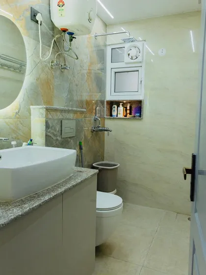 A look at a completed bathroom with marble-patterned tiles, an oval backlit mirror, and a sleek vanity unit.