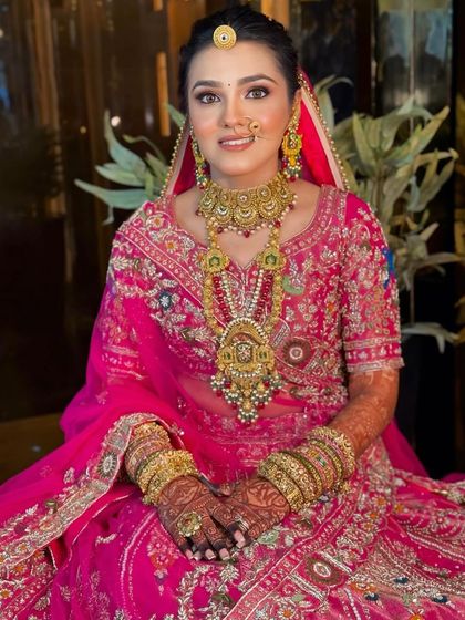 A beautiful bride in a heavily embroidered pink lehenga. Her makeup is kept soft and radiant to balance the intricate outfit, with a focus on flawless skin and defined features.