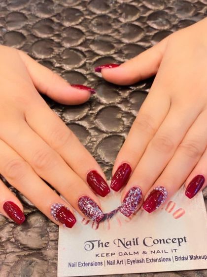 A rich and glamorous design on coffin-shaped nails. The deep red polish is paired with accent nails featuring a dense cluster of multi-tonal glitter.